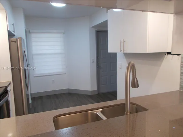 an empty room with wooden floor chandelier fan and windows