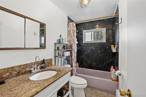 a bathroom with a sink a toilet a mirror a bathtub and shower