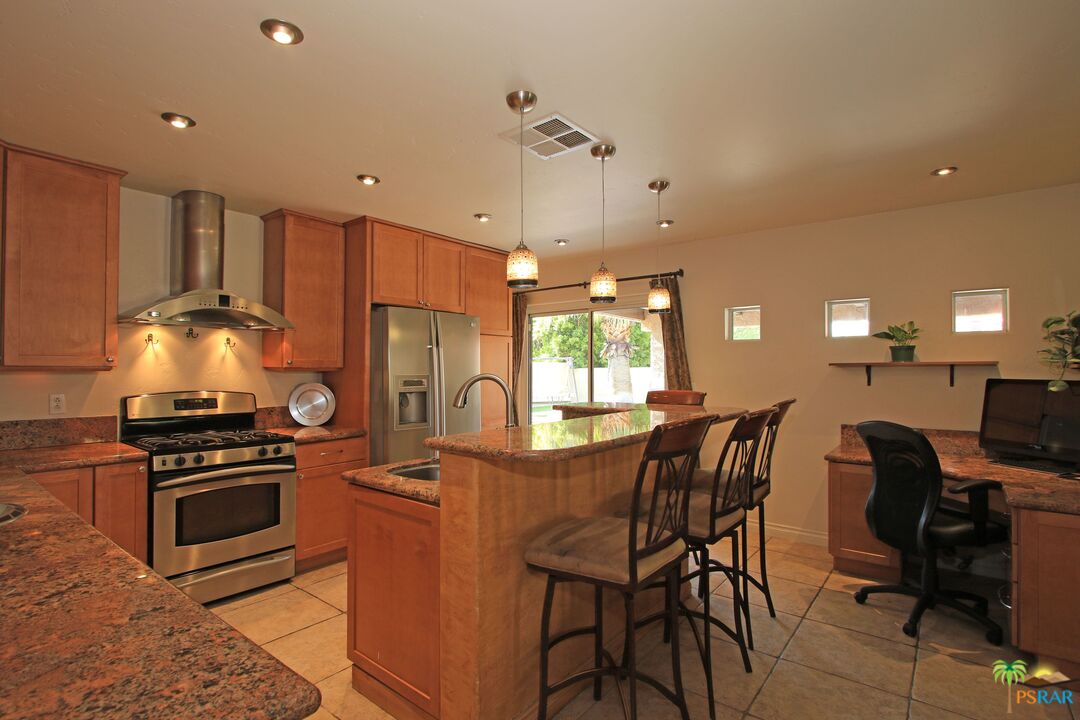 2288 North Deborah Road Palm Springs, CA 92262 - Photo 11 of 33 a kitchen with stainless steel appliances a table chairs and a refrigerator