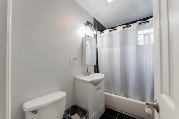 a bathroom with a sink a toilet a mirror and shower curtain