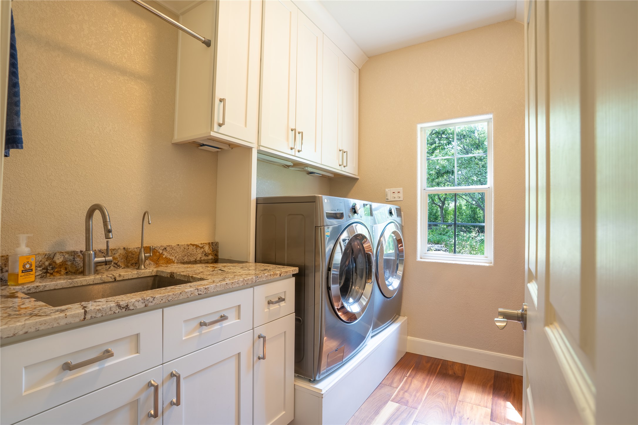 13800 Lone Rider Trail Austin, TX 78738 - Photo 14 of 32 Functional laundry room featuring a utility sink and ample cabinetry for streamlined chores.