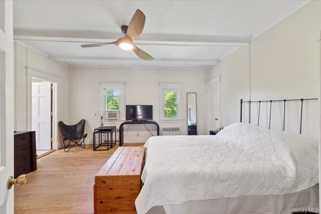 a bed room with a bed a chair and potted plant on the dresser