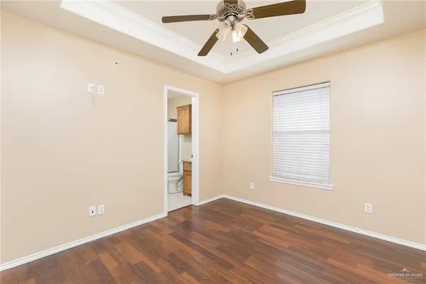 an empty room with wooden floor windows and fan
