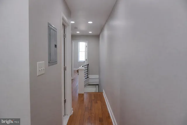 a view of a hallway with wooden floor and a bathroom