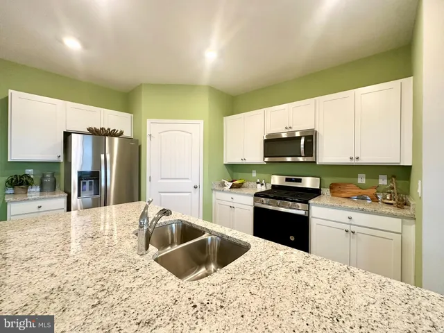a kitchen with granite countertop a stove sink and refrigerator