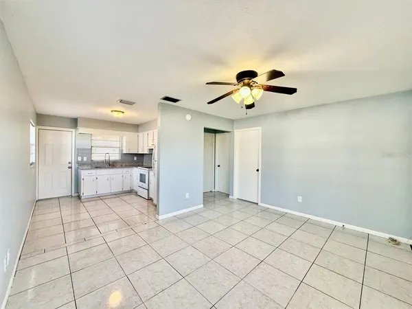 a view of an empty room and kitchen view