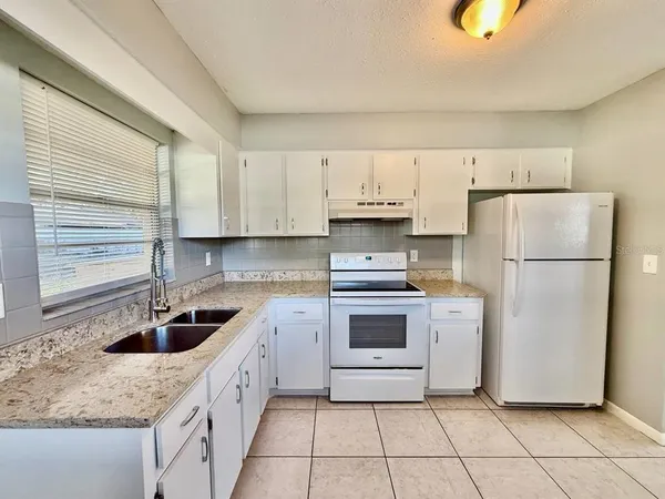 a kitchen with white cabinets and white appliances