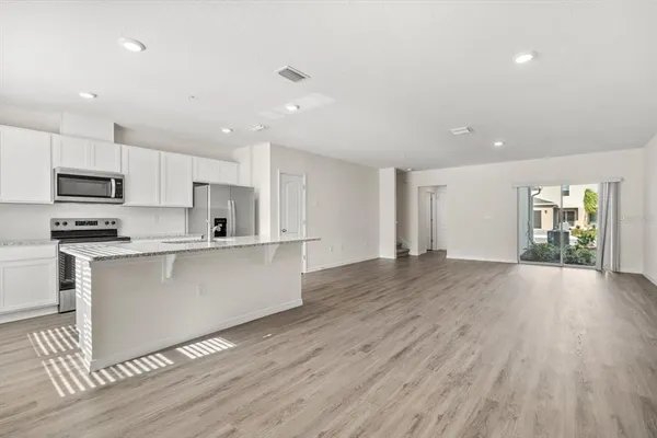 a kitchen with stainless steel appliances granite countertop a refrigerator a sink a stove a microwave and island