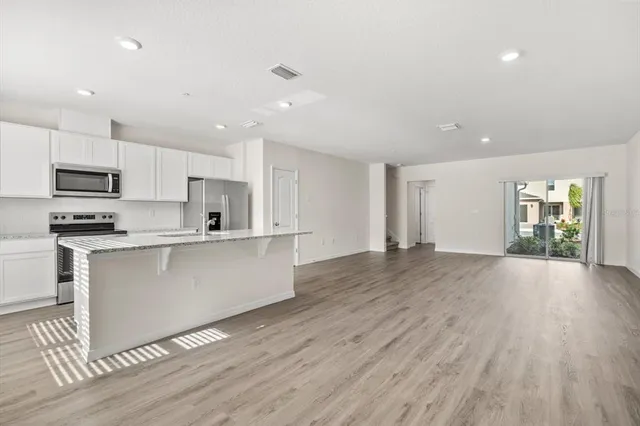 a kitchen with stainless steel appliances granite countertop a refrigerator a sink a stove a microwave and island