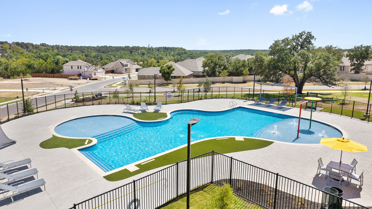 113 Shadow Oak Cove Georgetown, TX 78628 - Photo 39 of 40 An inviting community pool with splash pad awaits, bordered by residential homes and a scenic natural backdrop.
