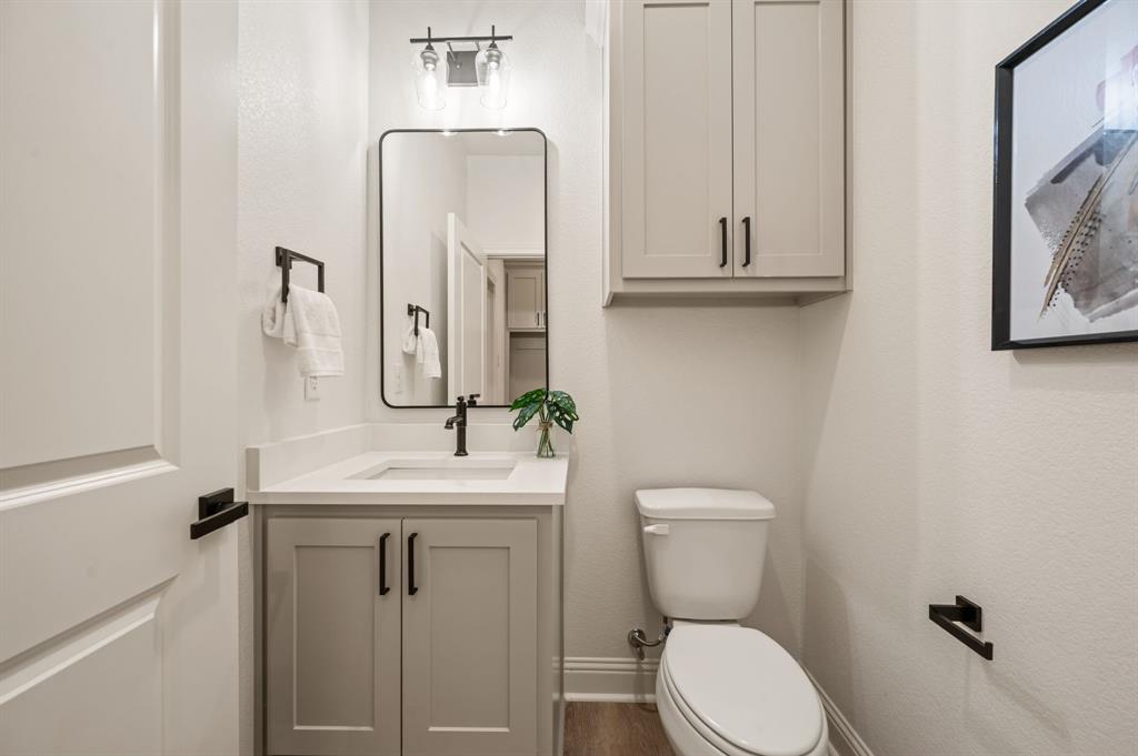 2705 Gospel Road Tolar, TX 76476 - Photo 17 of 36 Modern powder room featuring a rectangular black-framed mirror, light gray vanity with black hardware, white countertop with integrated sink, and luxury vinyl flooring