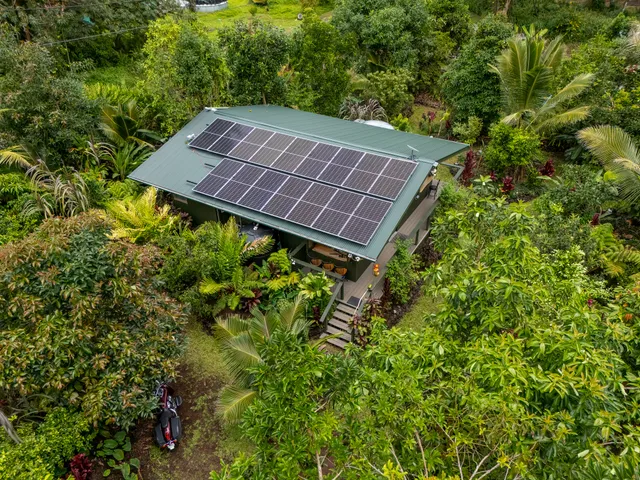 a view of a house with a street and trees all around