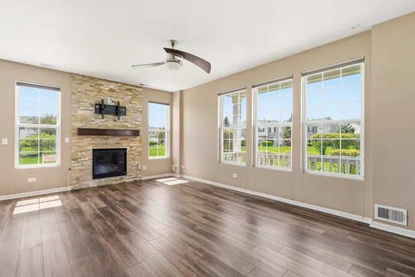 a view of an empty room with wooden floor fireplace and a window