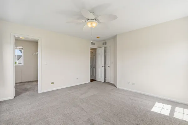 an empty room with closet and a ceiling fan