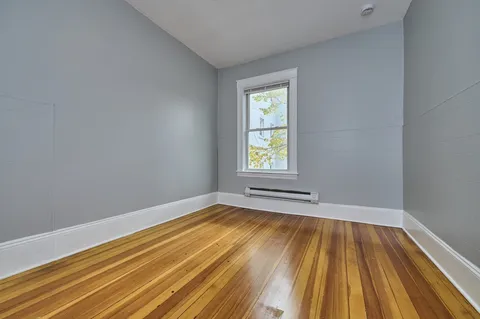 a view of empty room with window and wooden floor