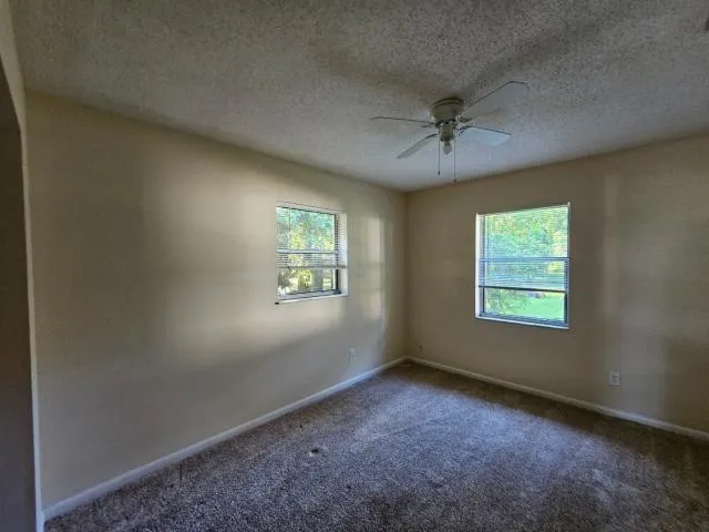 an empty room with windows and fan