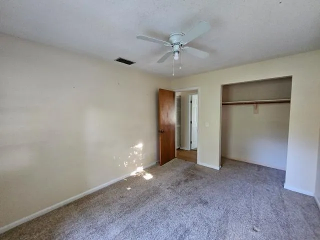 an empty room with closet and a chandelier fan