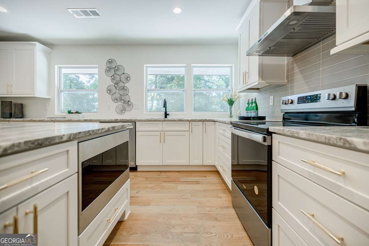 3154 North Druid Hills Road Decatur, GA 30033 - Photo 40 of 84 a kitchen with granite countertop stainless steel appliances a stove sink and microwave