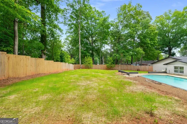a view of a swimming pool with a yard and large trees