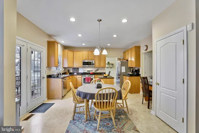 a kitchen with stainless steel appliances granite countertop a stove top oven a sink a refrigerator white cabinets and wooden floor