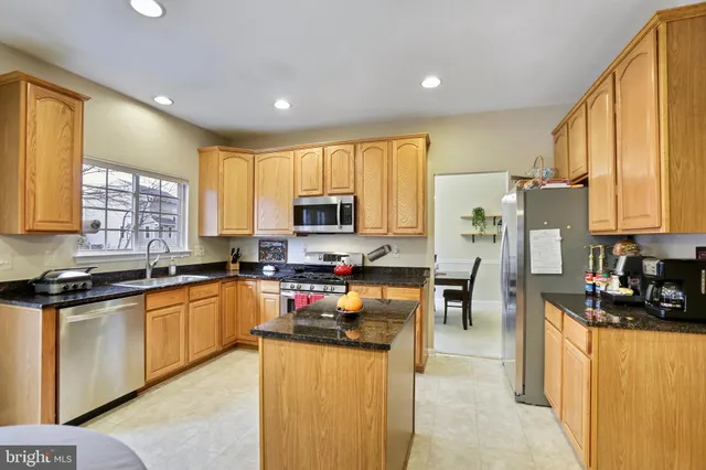 a kitchen with granite countertop a stove top oven microwave and refrigerator