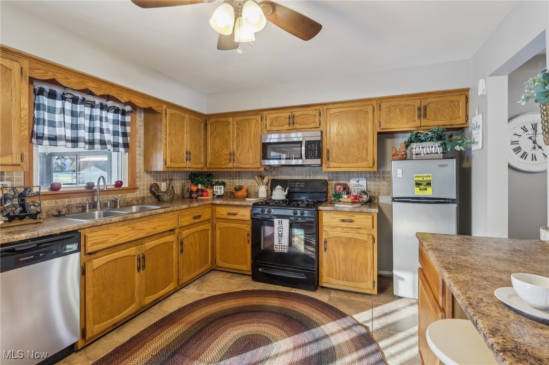 2634 Brunswick Road Youngstown, OH 44511 - Photo 10 of 50 Kitchen with ceiling fan, sink, stainless steel appliances, decorative backsplash, and light tile patterned floors