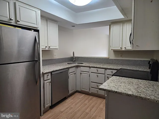 a kitchen with a sink a refrigerator and cabinets