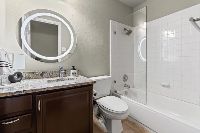 a bathroom with a granite countertop sink toilet and a mirror