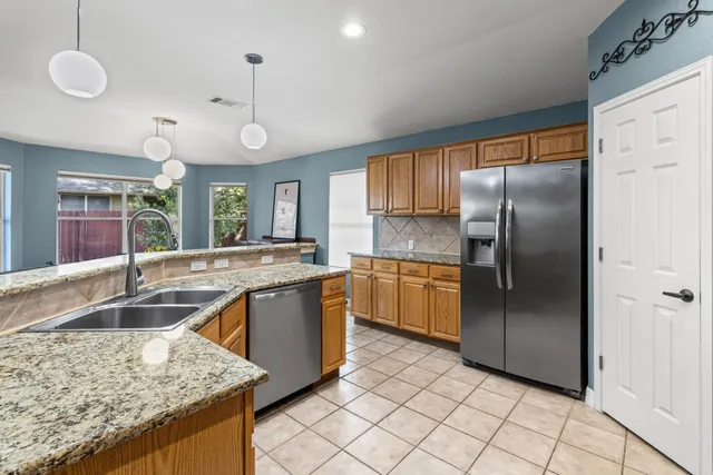 a kitchen with stainless steel appliances granite countertop a sink a stove and a refrigerator