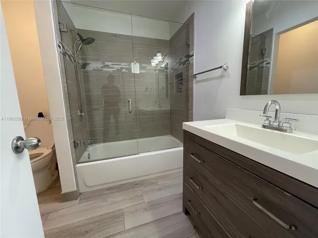 a bathroom with a bathtub shower sink vanity and a toilet