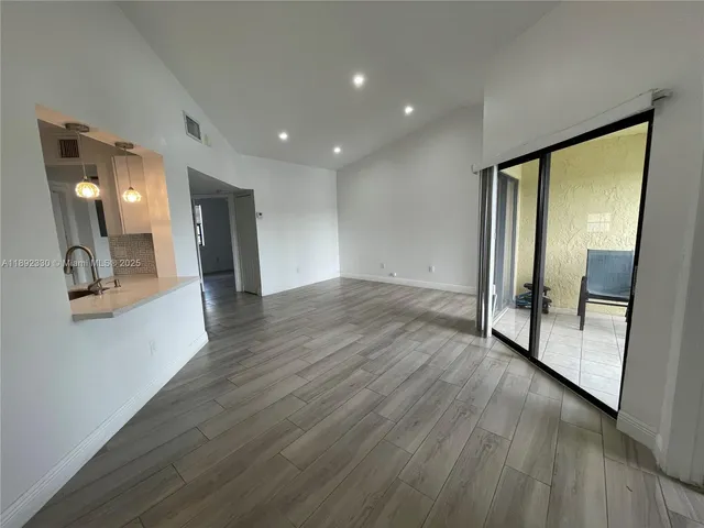 a view of a hallway with wooden floor and a mirror