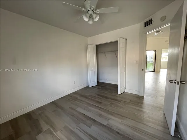 an empty room with wooden floor and a ceiling fan