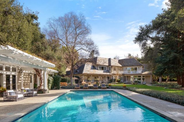 a swimming pool view with a seating space and a garden view