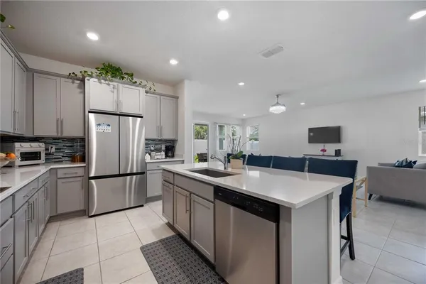 a view of a kitchen with kitchen island a sink appliances and a living room