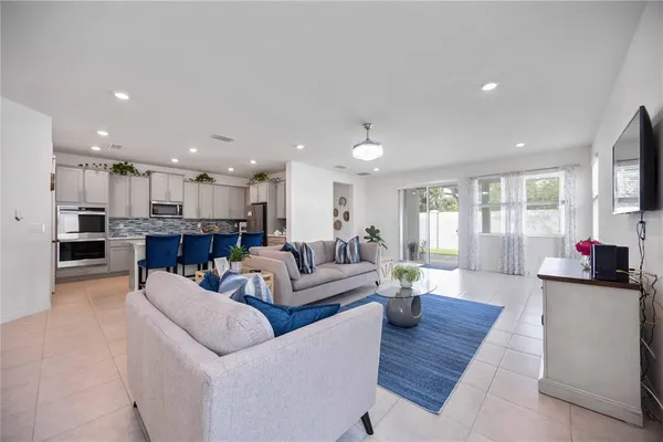 a living room with furniture potted plant and kitchen view