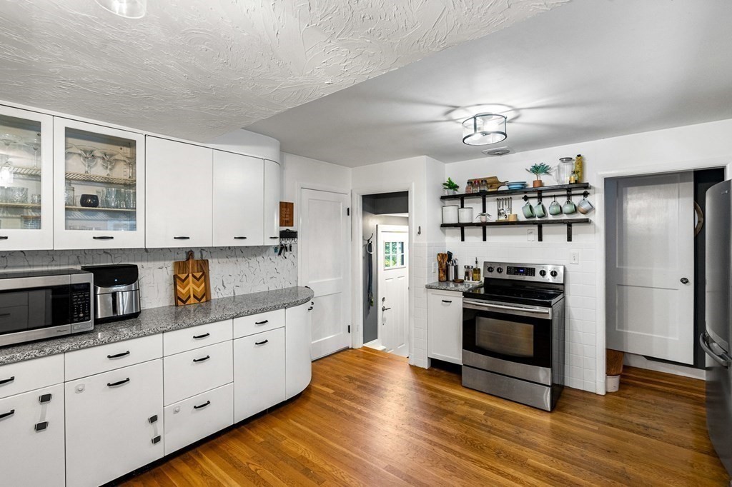 70 Indian Hill Road Worcester, MA 01606 - Photo 7 of 34 a kitchen with stainless steel appliances kitchen island granite countertop a refrigerator a stove cabinets and wooden floor