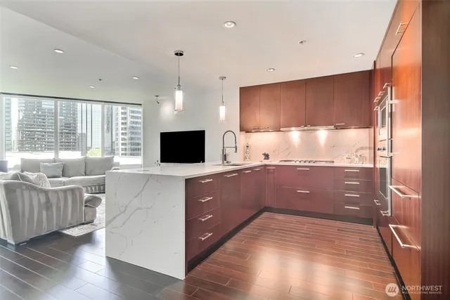 a large kitchen with a large counter top a sink a window and stainless steel appliances