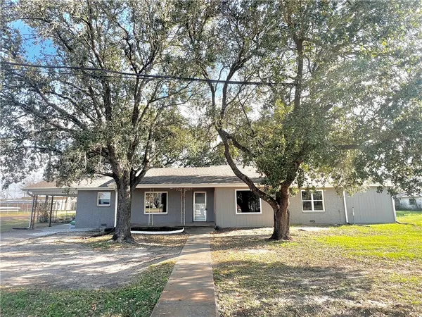 a front view of a house with a garden and trees