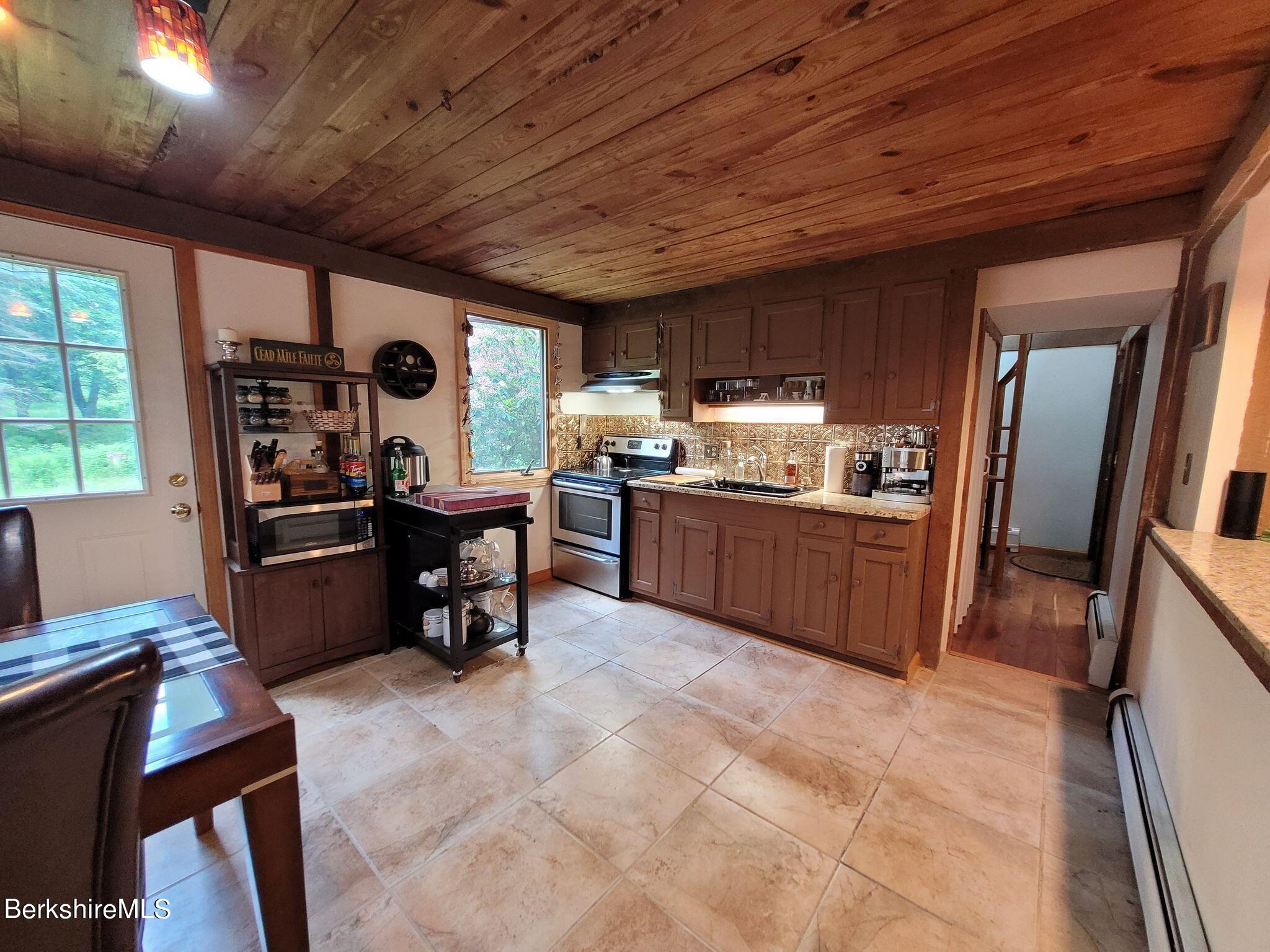 106 Access Road Becket, MA 01223 - Photo 11 of 43 a kitchen with stainless steel appliances kitchen island granite countertop a table chairs and a refrigerator