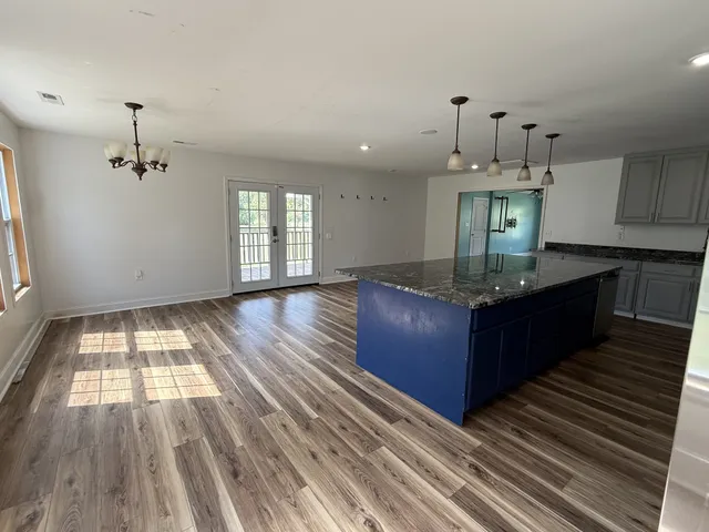 a large kitchen with stainless steel appliances kitchen island granite countertop a refrigerator and a sink