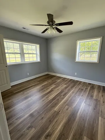 an empty room with wooden floor and windows