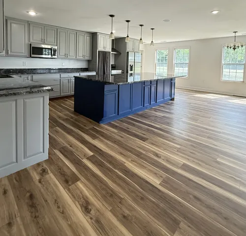 a kitchen with stainless steel appliances granite countertop wooden cabinets a refrigerator a sink a stove and wooden floors