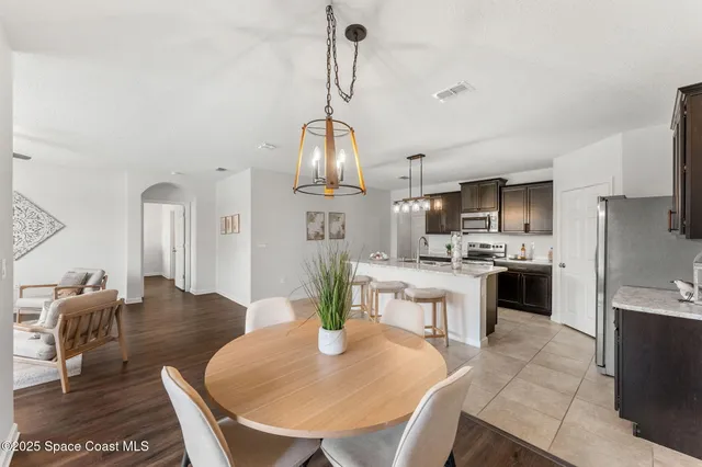 a kitchen with a dining table chairs and refrigerator