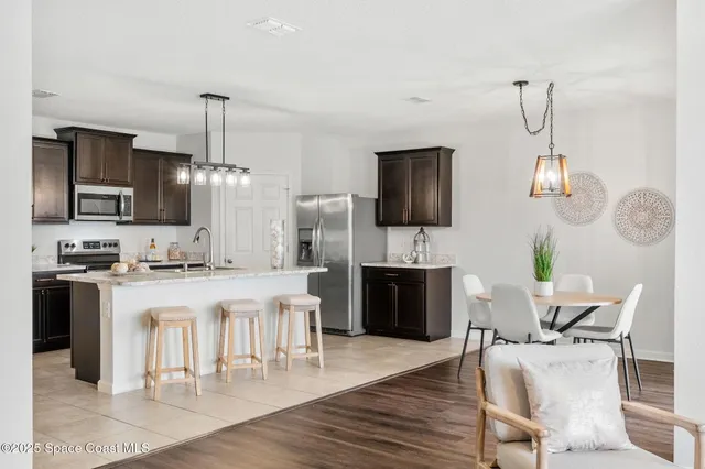 a kitchen with stainless steel appliances granite countertop a stove top oven a sink dishwasher a dining table and chairs with wooden floor