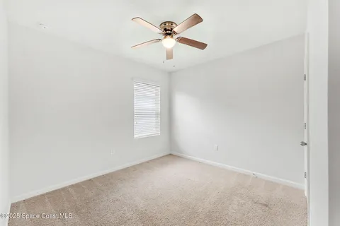 an empty room with window and ceiling fan