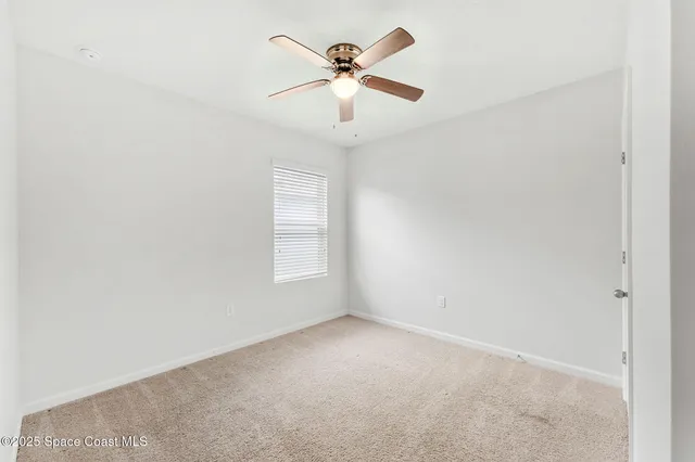 an empty room with window and ceiling fan