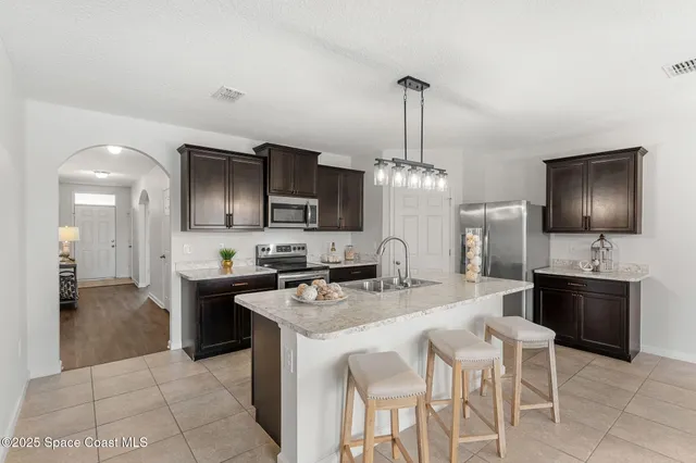 a kitchen with stainless steel appliances granite countertop a stove top oven a sink dishwasher a dining table and chairs with wooden floor