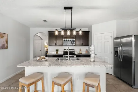 a kitchen with kitchen island granite countertop a table chairs stove and refrigerator