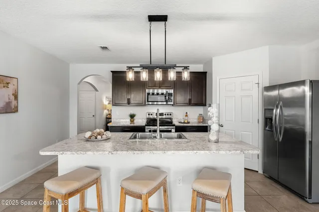 a kitchen with kitchen island granite countertop a table chairs stove and refrigerator
