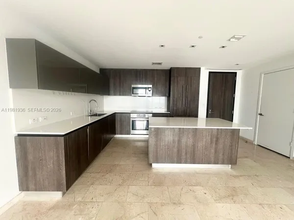 a large kitchen with stainless steel appliances kitchen island granite countertop a refrigerator a sink and a stove